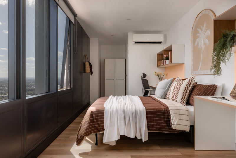 Modern bedroom with large windows, bed, and desk.