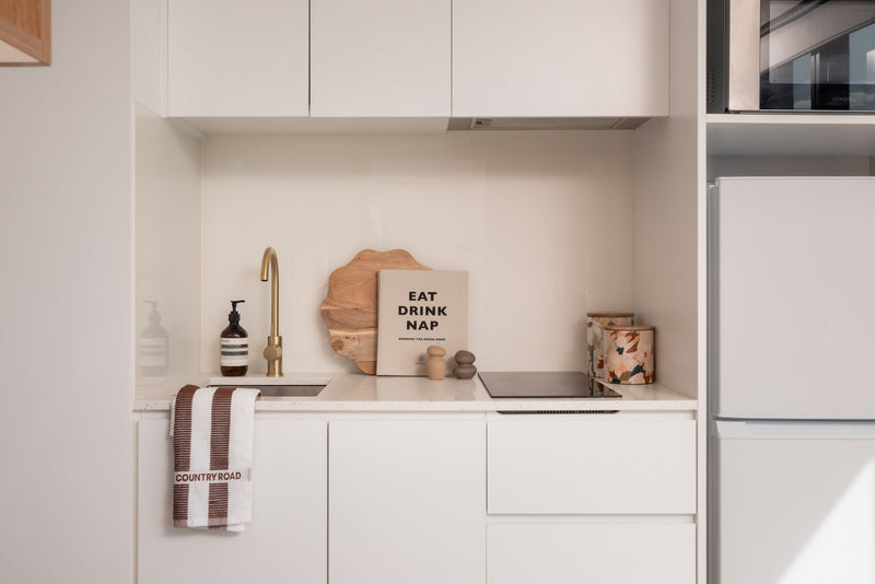 Modern kitchen with white cabinets, a sink, and various kitchen items.