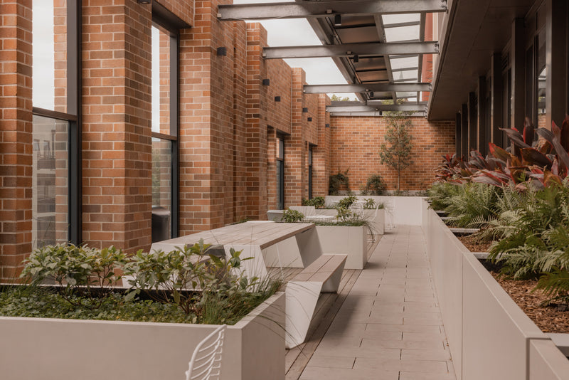 Outdoor patio area with brick walls, concrete benches, and greenery.