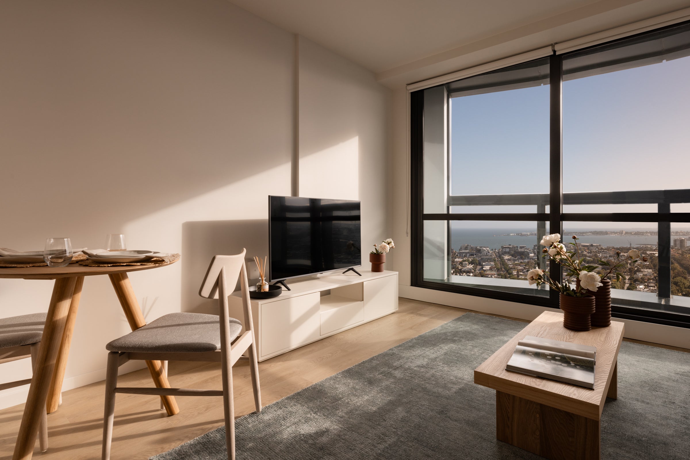 Commercial apartment styled with neutral furnishings, timber accents and city views, designed to support leasing and marketing campaigns by Embestro Interiors.